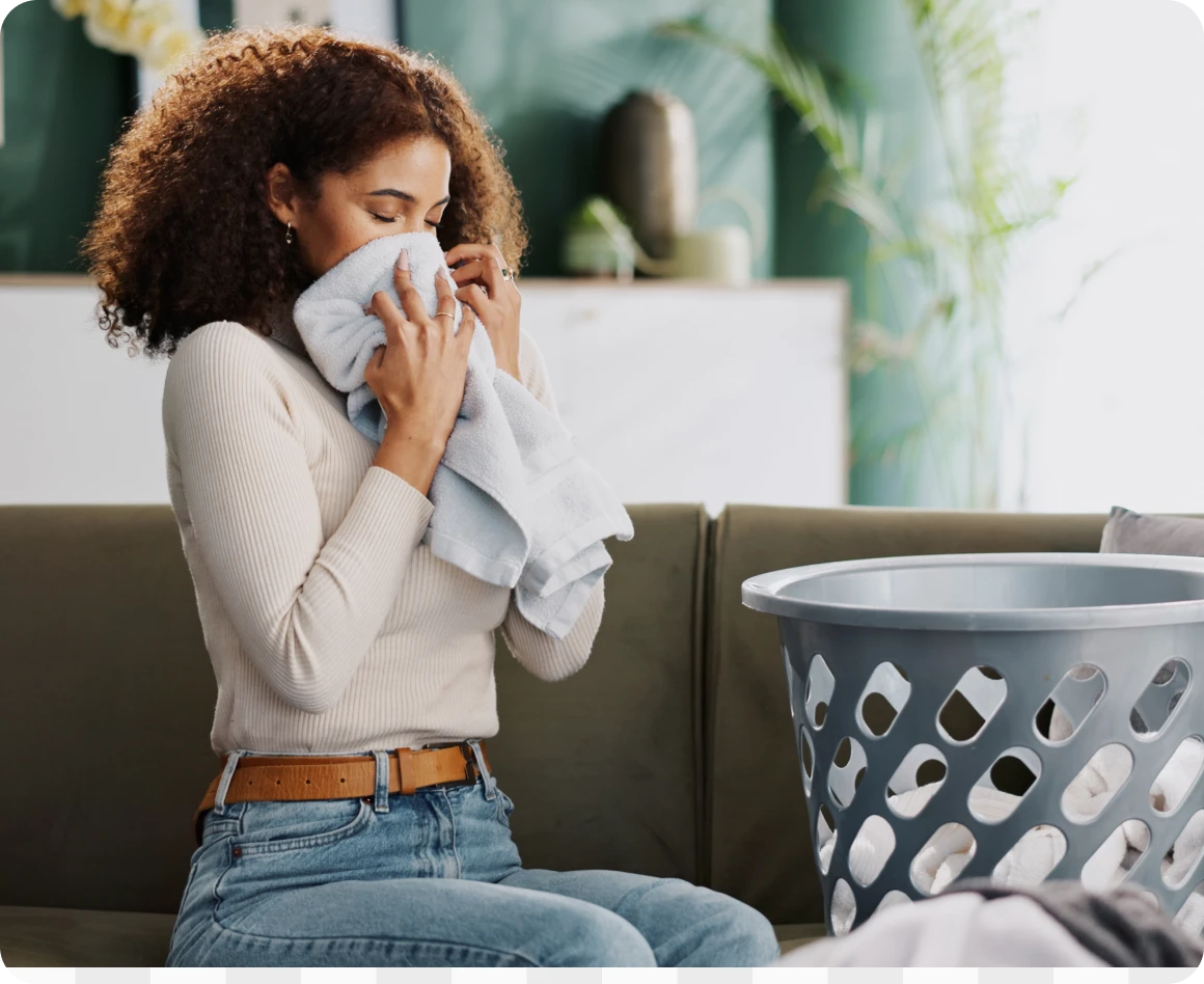 Woman enjoying fresh laundry scent indoors.