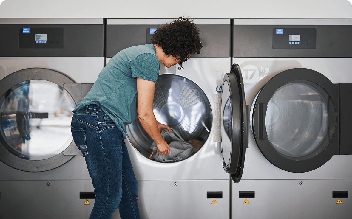 A woman loading clothes into a front-loading washing machine.