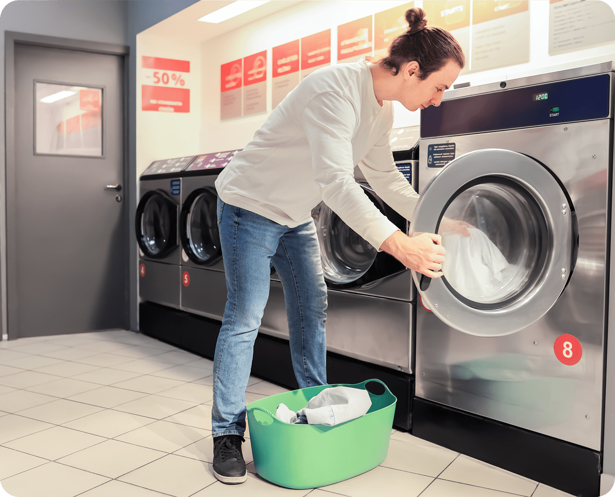 Woman loading laundry into a washing machine at a laundromat.