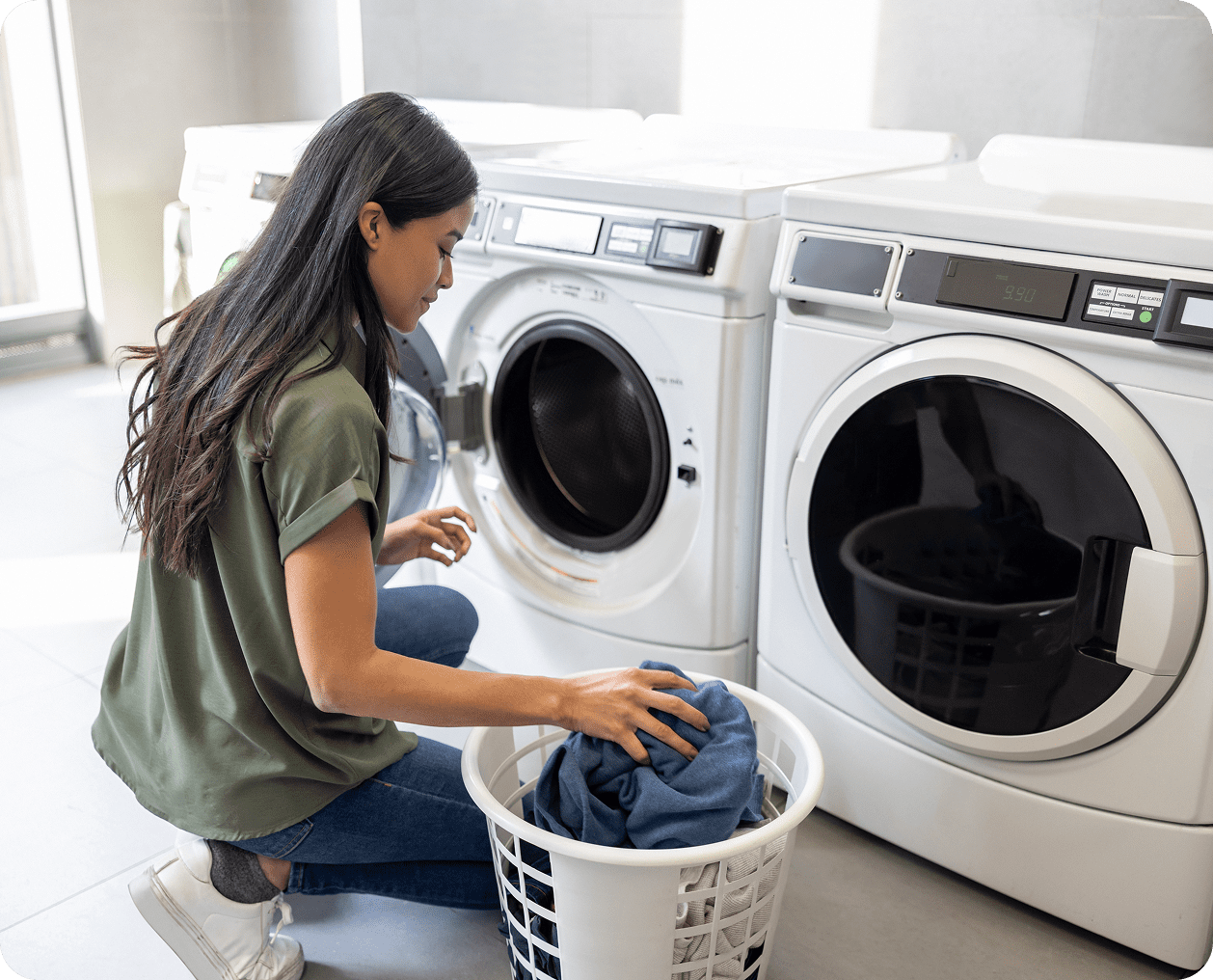 Woman loading laundry into a front-loading washing machine.