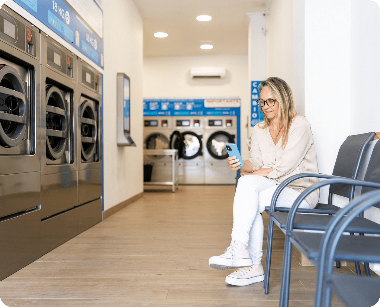 Woman waiting in a laundromat, seated on a chair.