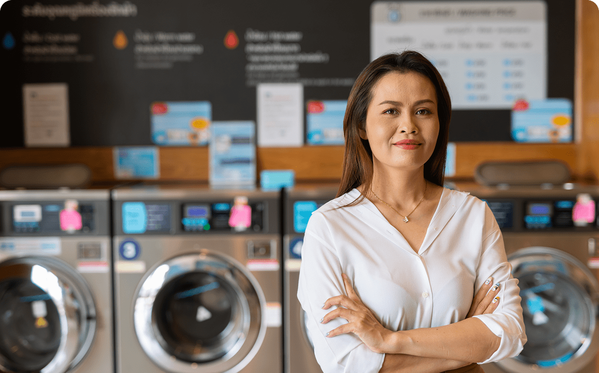 Confident woman standing in a laundromat with arms crossed.